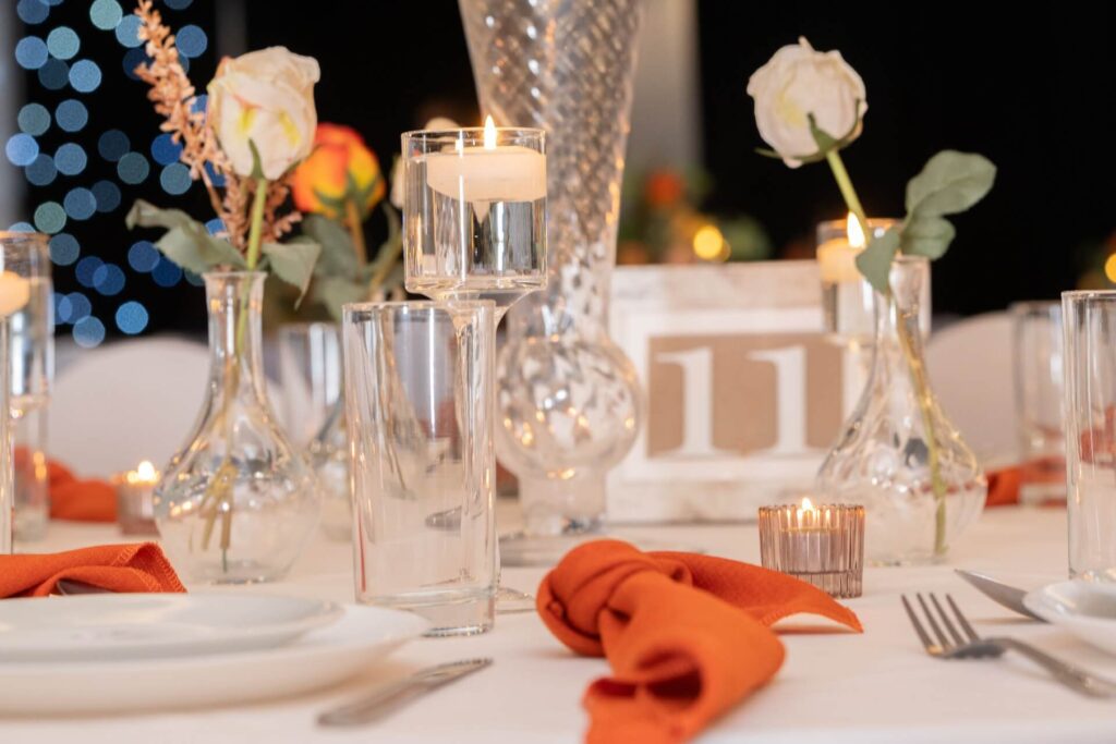 Rustic wedding decor with bud vases, linen napkins, and elegant centrepieces in a modern venue setting.