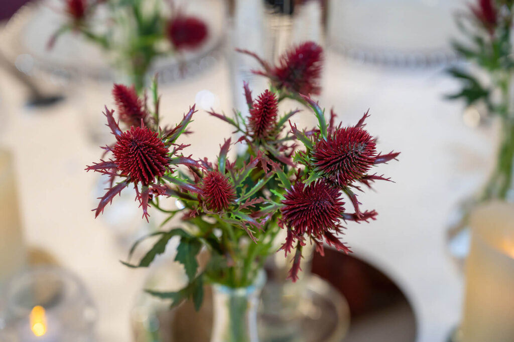 Bud vase flower arrangements on Morley Town Hall wedding tables – delicate blooms in glass vases with ivory chair sashes.