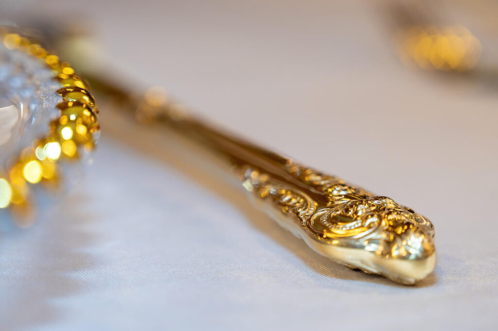 Luxury 50th birthday table setting in Morley with engraved gold cutlery, crystal glassware, and fresh floral arrangements for an elegant celebration.