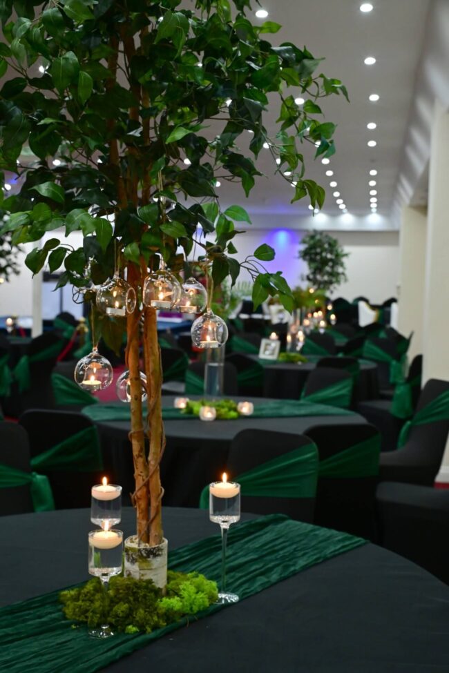 Ficus tree centerpieces with hanging glass candle holders and green decor for elegant party tables.