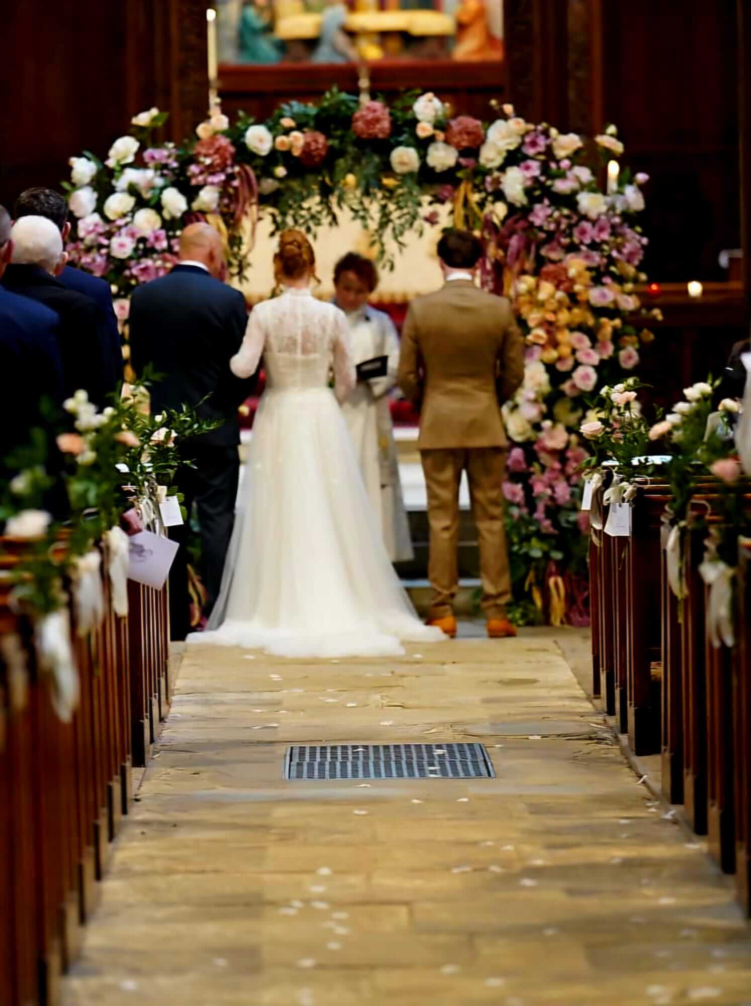 Stage decor featuring a bride and groom beneath a large pink and cream floral arch