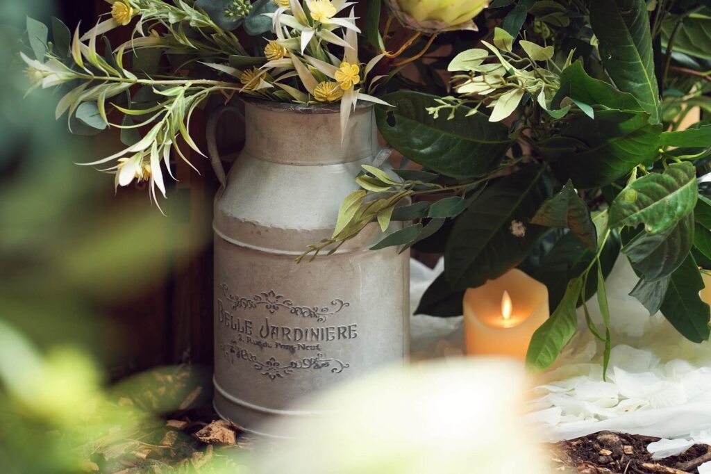 Decorative milk churn filled with flowers and foliage for a rustic event display