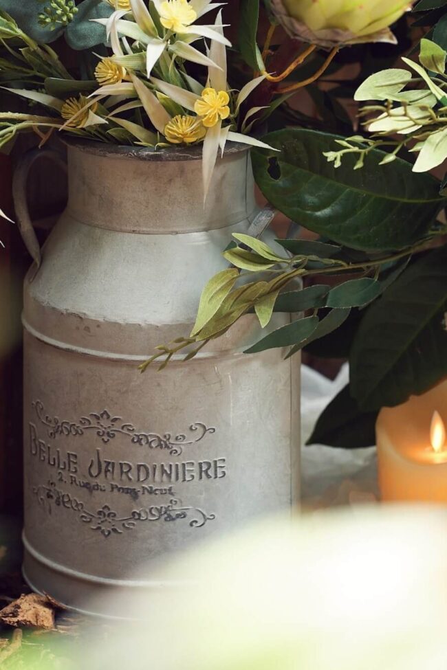 Decorative milk churn filled with flowers and foliage for a rustic event display