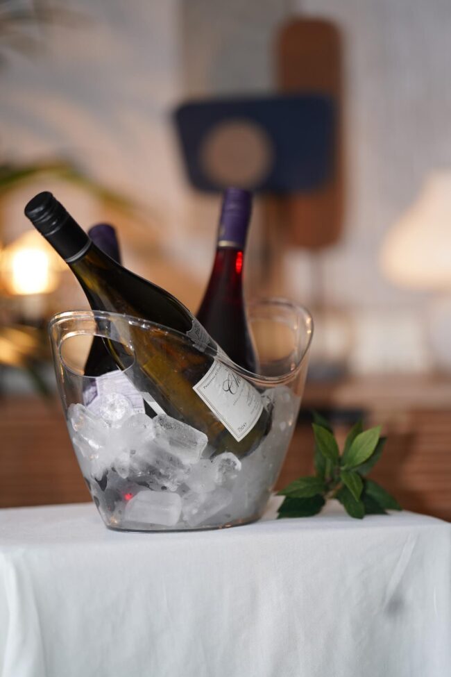 Clear ice bucket with wine bottles chilled in ice on a table