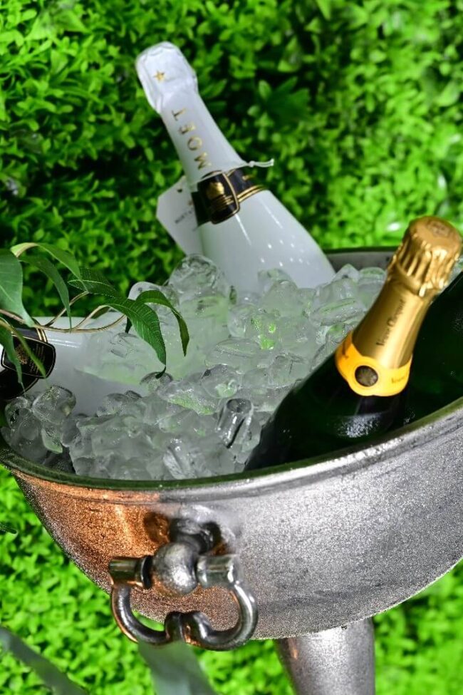 Large silver champagne bowl filled with ice and bottles of champagne