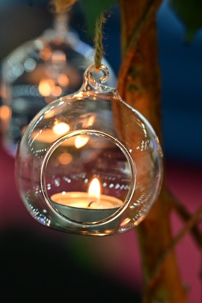 Clear hanging tealight holder suspended from a decorative branch