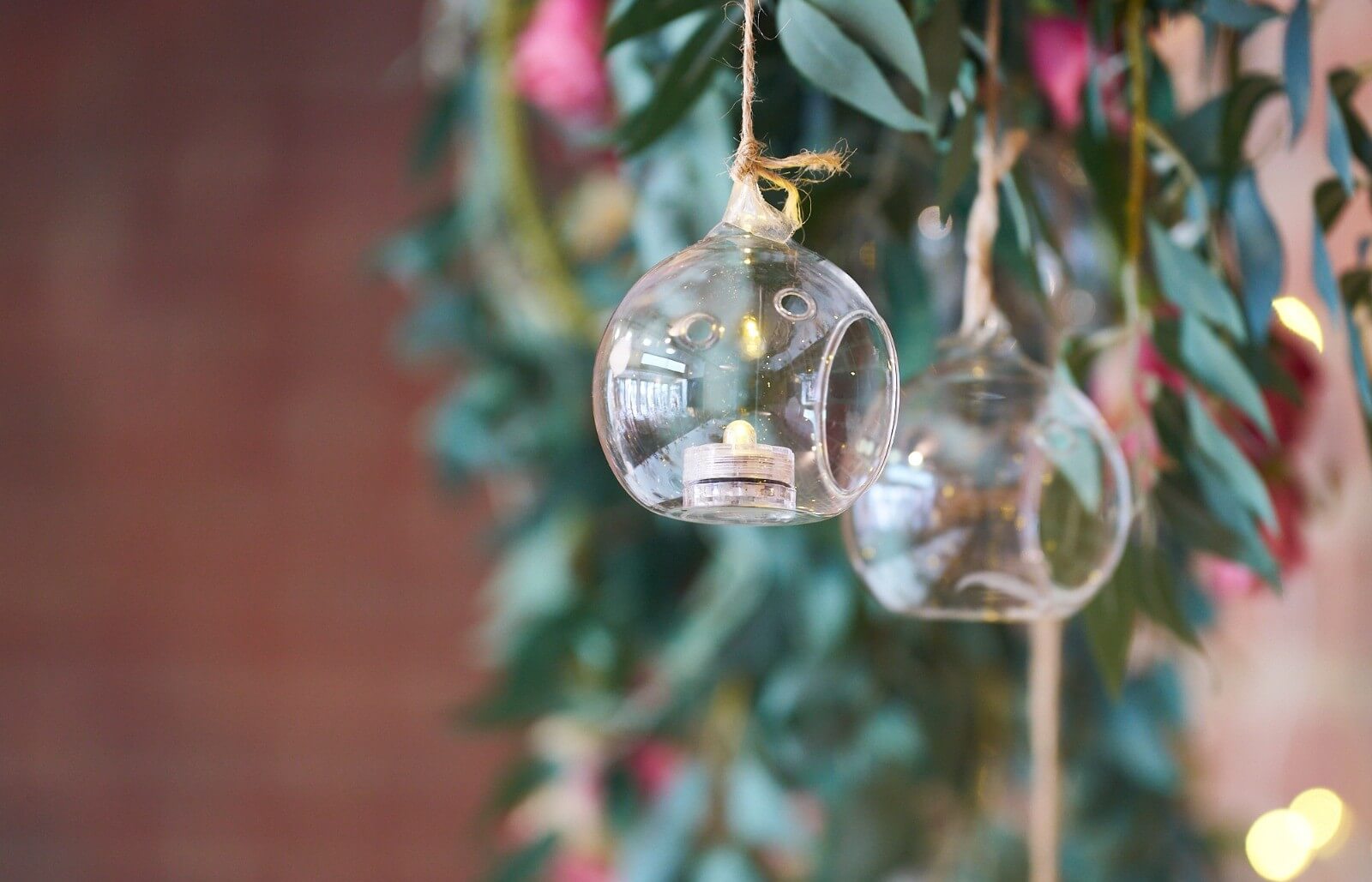 Glass hanging tealight holders suspended among leafy branches