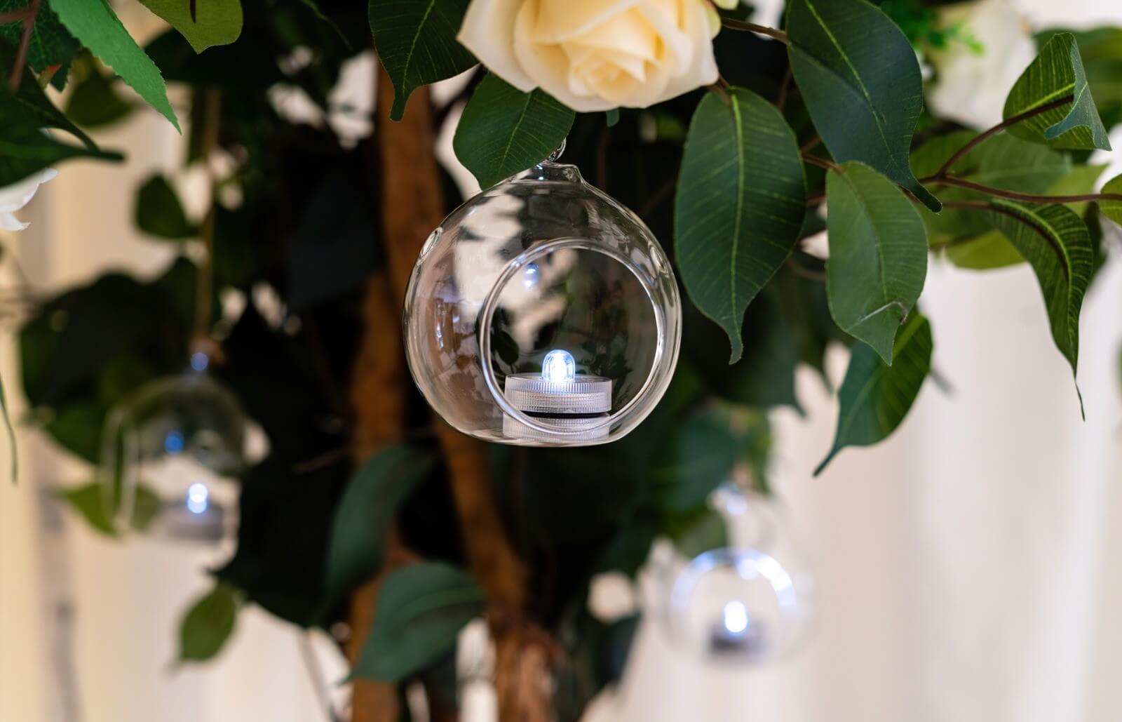 Hanging tealight holder suspended among green leaves and white flowers