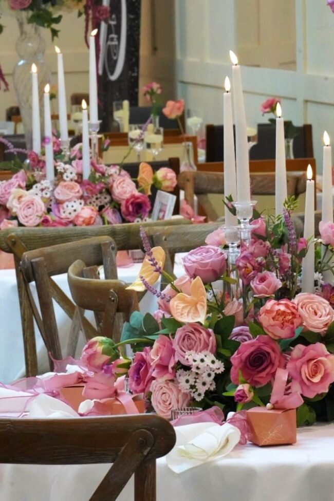 Acrylic candelabra with clear candle holders among pink flowers