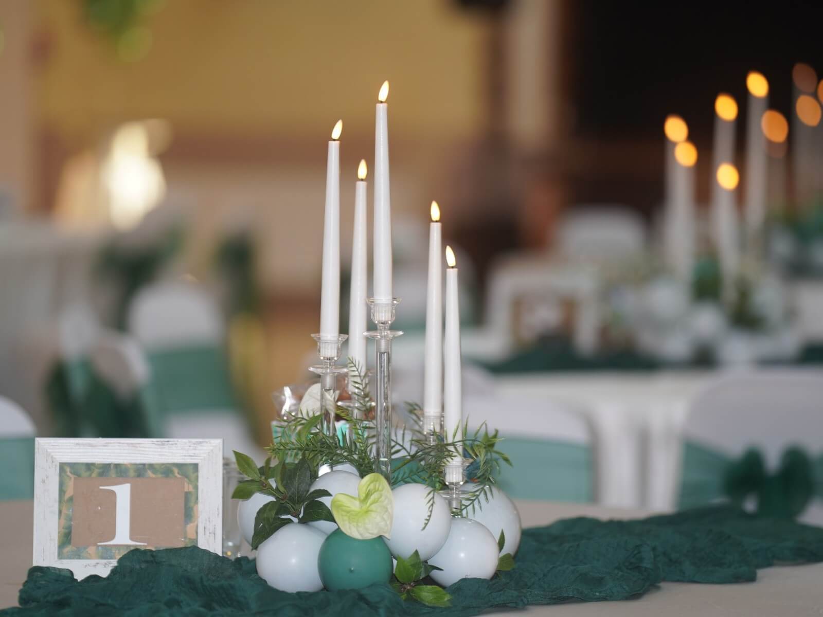 Elegant event styling with props featuring white candles, greenery and table decor in green and white tones.