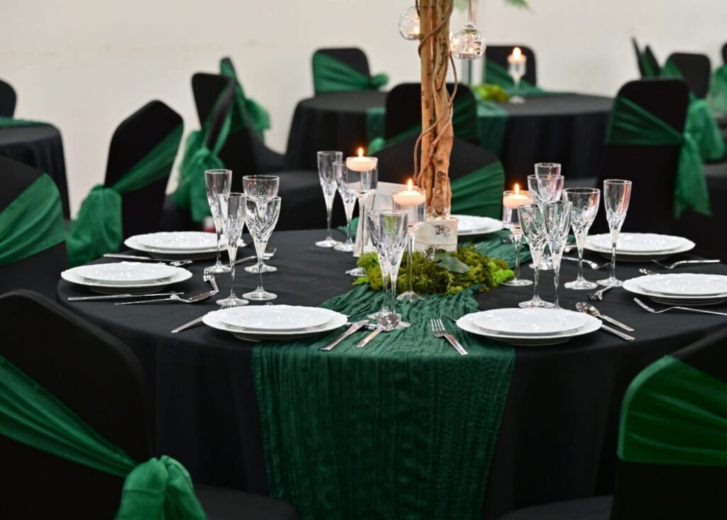 Black chair covers for hire with green sashes at an event