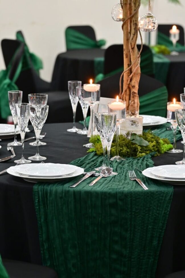 Black chair covers for hire with green sashes at an event