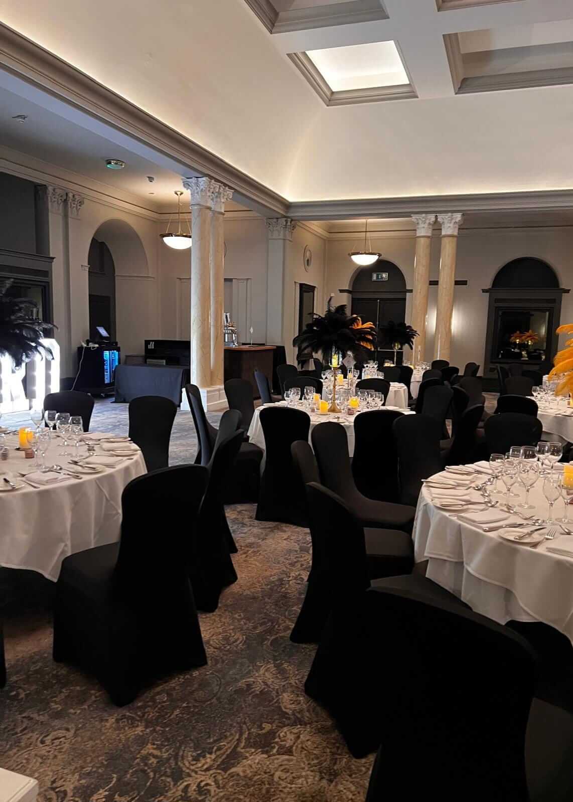 Black chair covers for hire styled for a formal banquet room setup