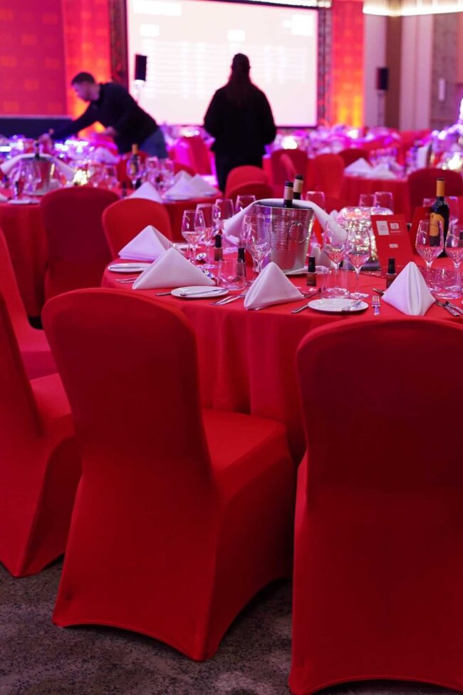 Red chair covers for hire around event tables