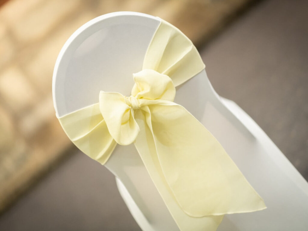 Cream sashes tied in a bow on a white venue chair