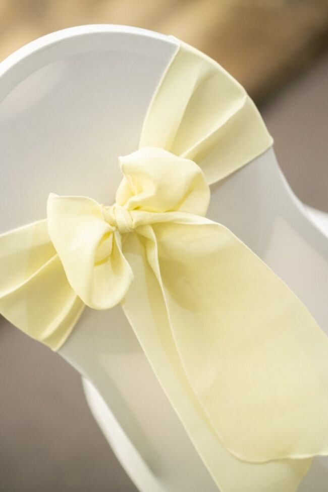 Cream sashes tied in a bow on a white venue chair
