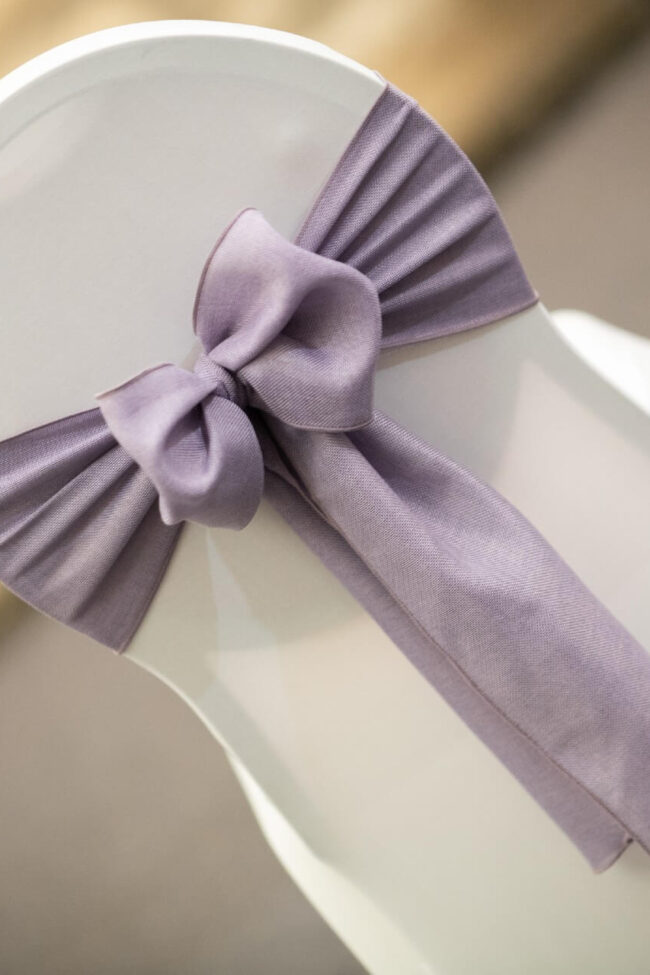 Lavender linen sashes tied in a neat bow on a white chair