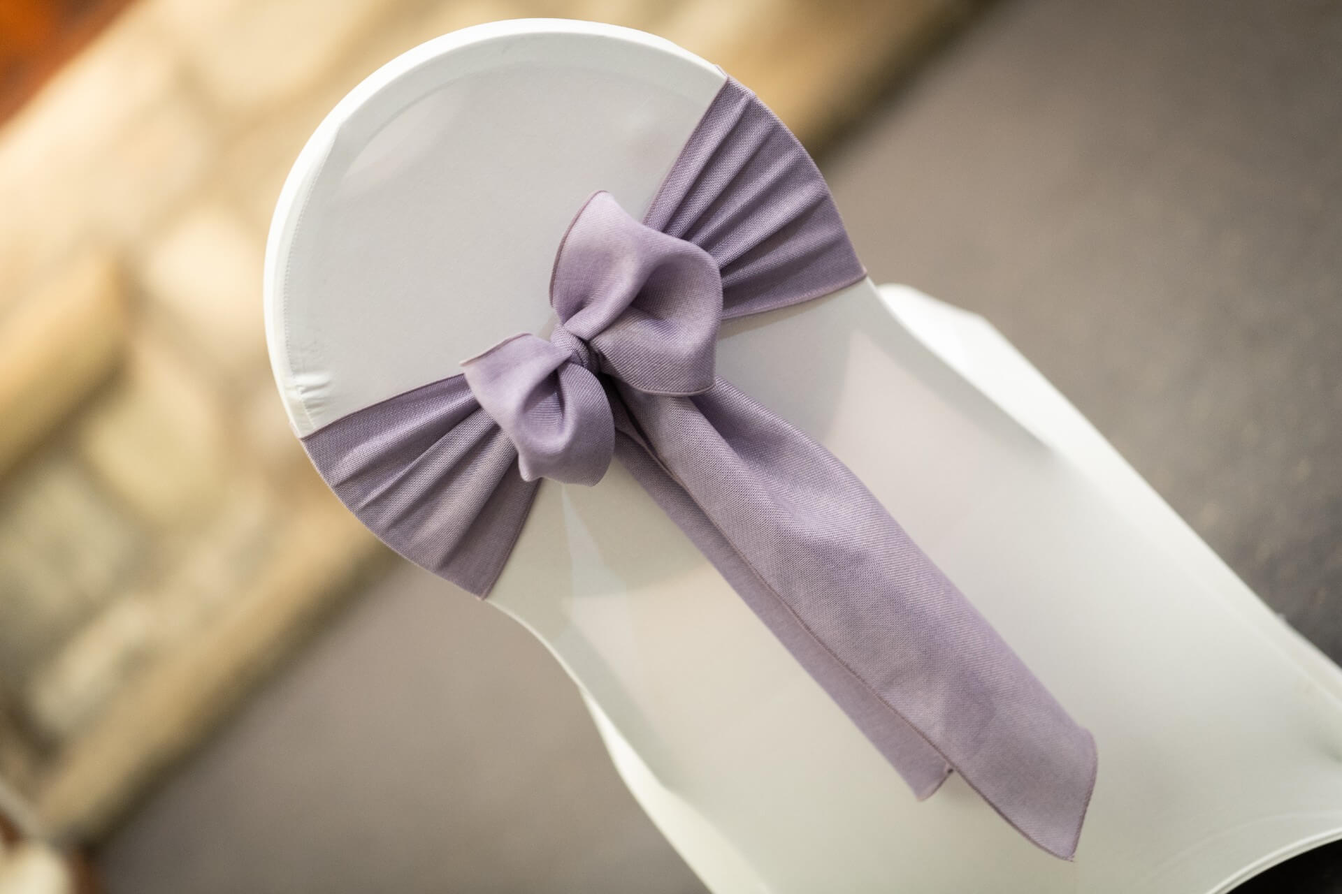Lavender linen sashes tied in a neat bow on a white chair