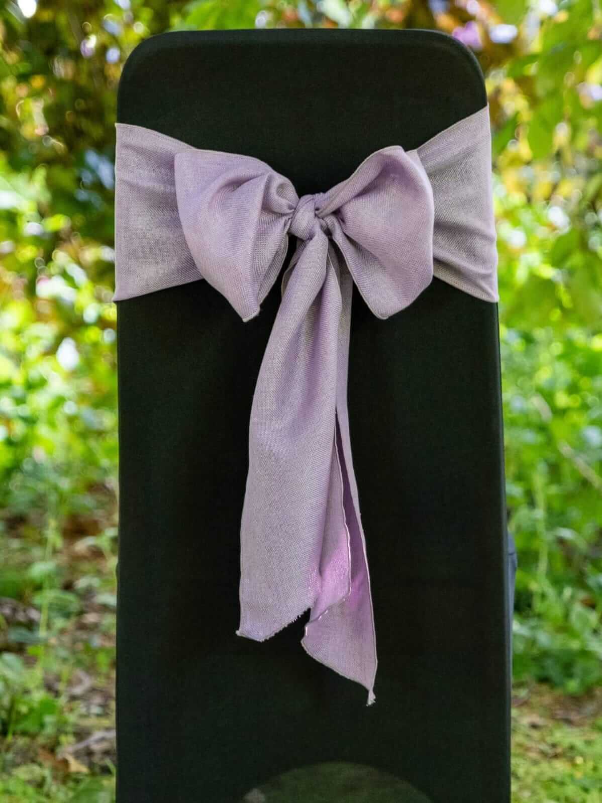 Purple sashes tied in a bow on a black chair for event seating