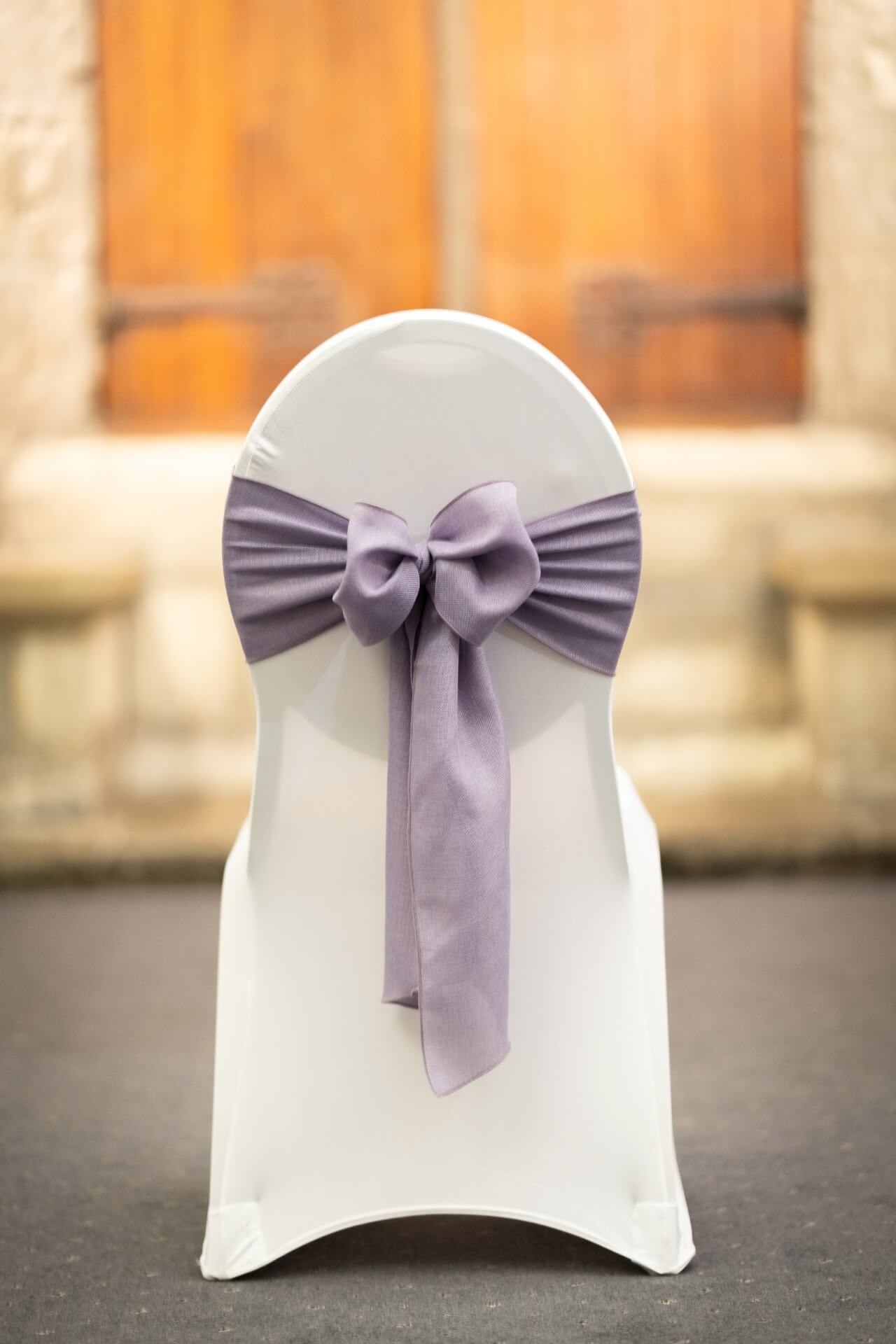 Lilac sashes bow style on a white chair cover, front view