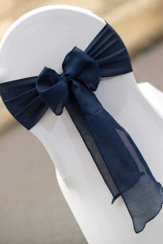 Navy chair sashes tied in a bow on a white chair cover