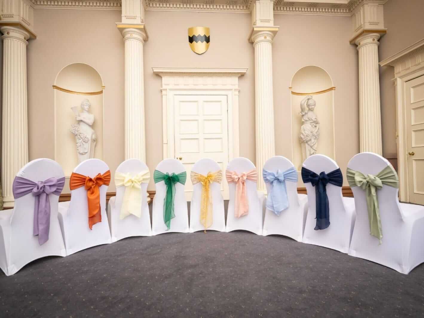 Chair sashes colour range displayed on white chair covers at a venue