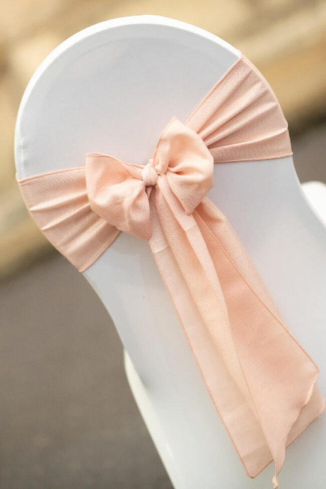 Pink sashes tied in a neat bow on a white chair cover