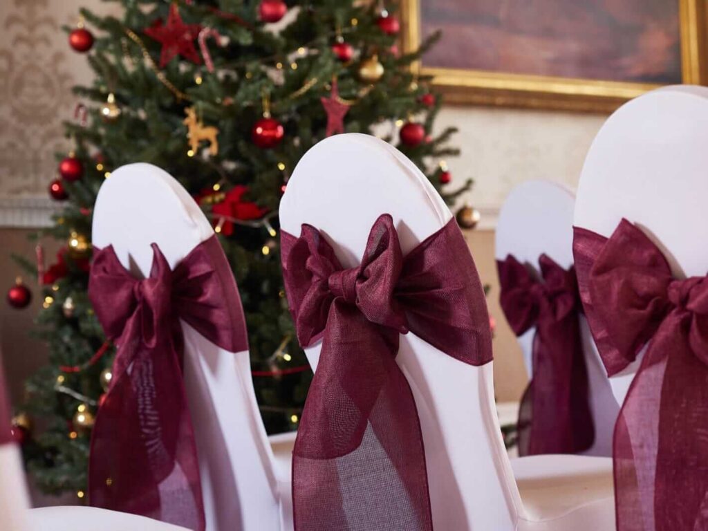 Red chair sashes in a burgundy shade on chair covers for a ceremony aisle setup