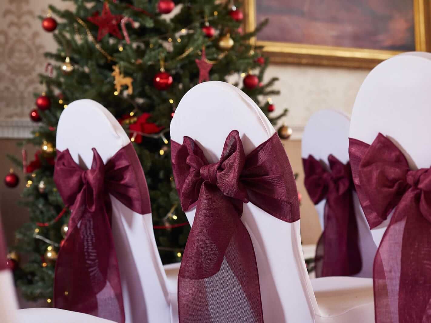 Red chair sashes in a burgundy shade on chair covers for a ceremony aisle setup