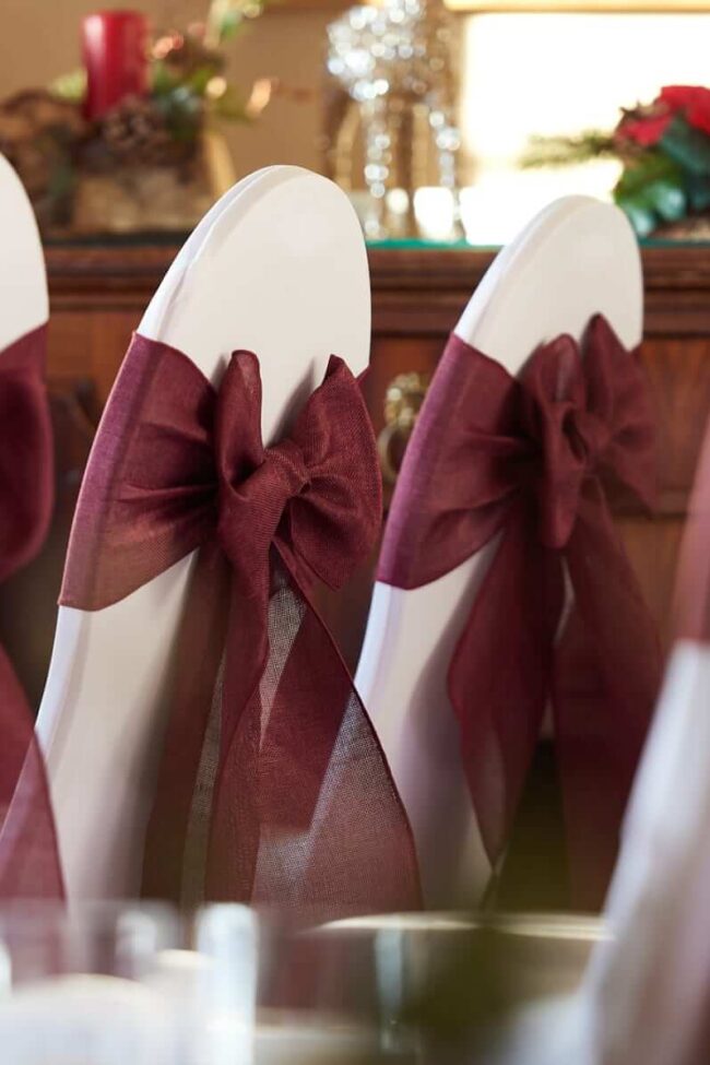 Burgundy chair sashes tied in bows across several chairs
