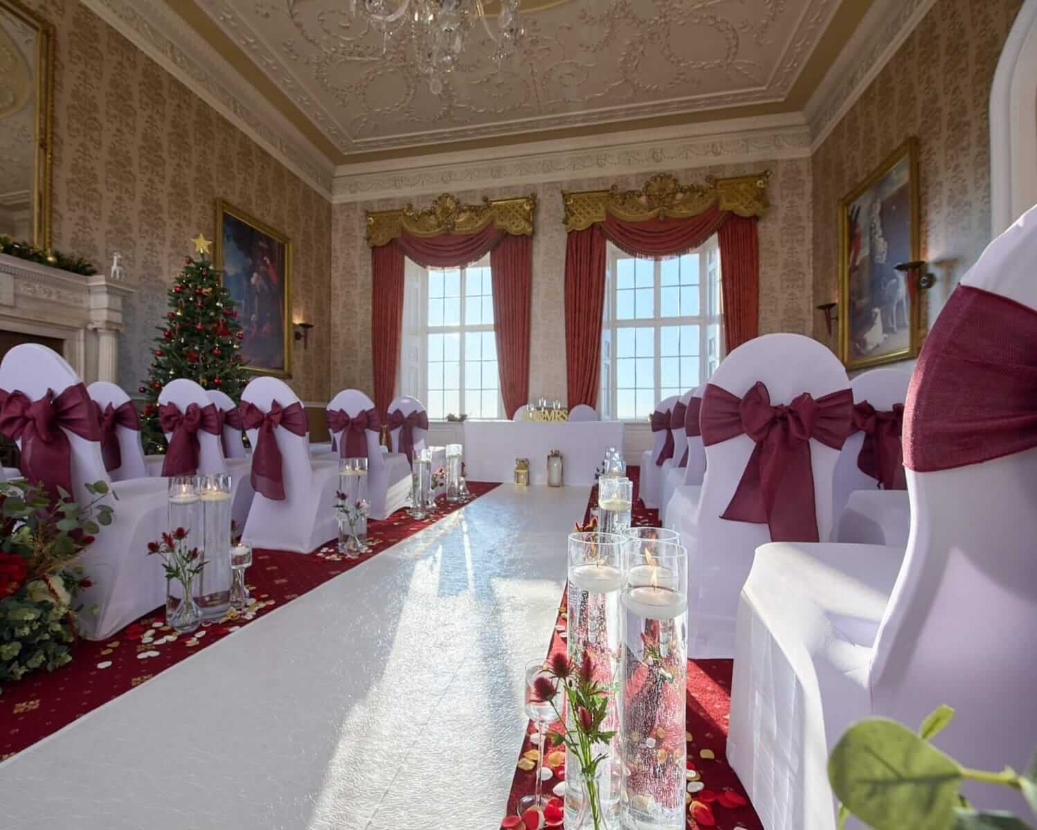 Burgundy chair sashes styled along ceremony seating with a white aisle runner