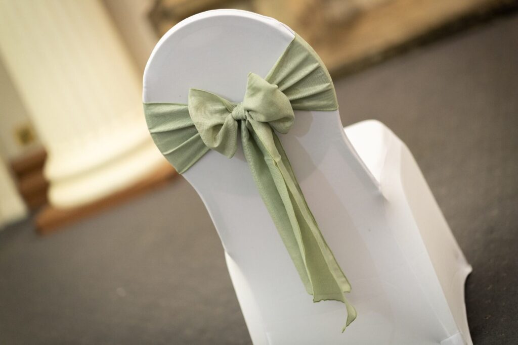 Sage burlap sash tied in a neat bow on a white chair cover