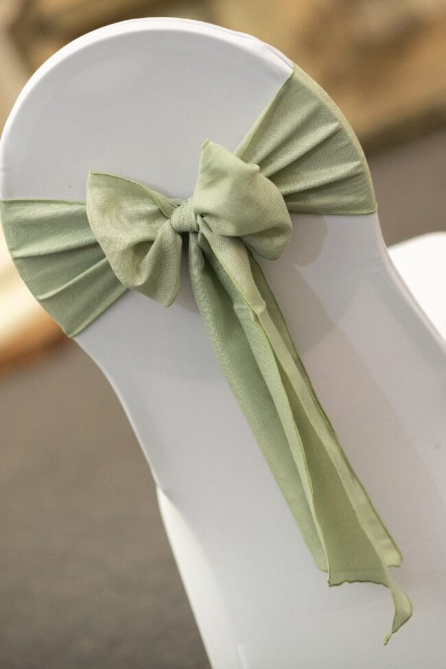Sage burlap sash tied in a neat bow on a white chair cover