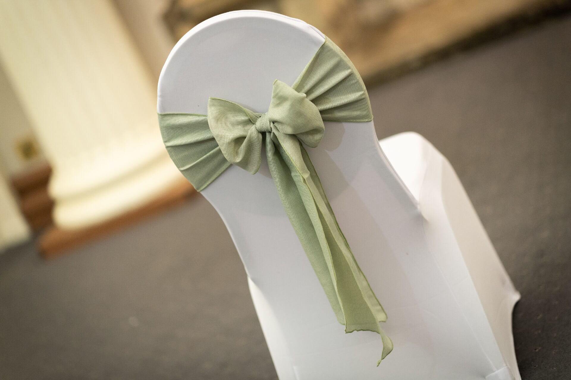 Sage burlap sash tied in a neat bow on a white chair cover