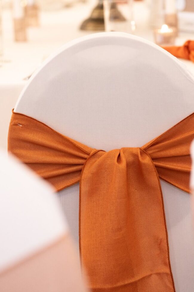 Close-up of terracotta sashes bow on white chair cover