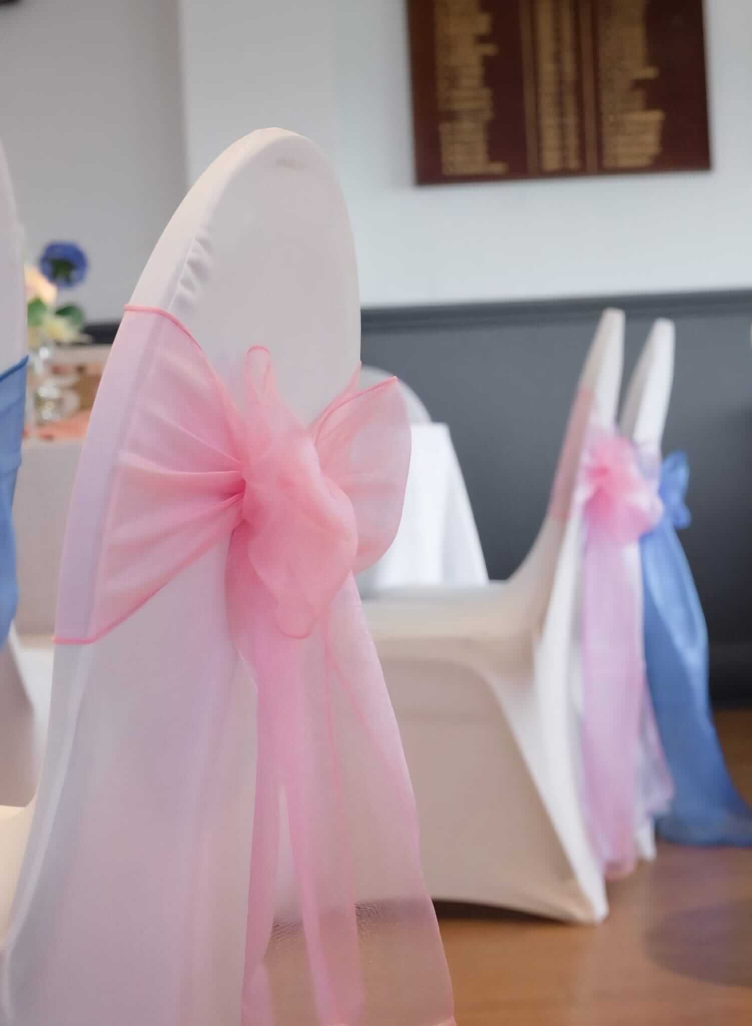 Raspberry pink sashes tied in a bow on a white chair cover