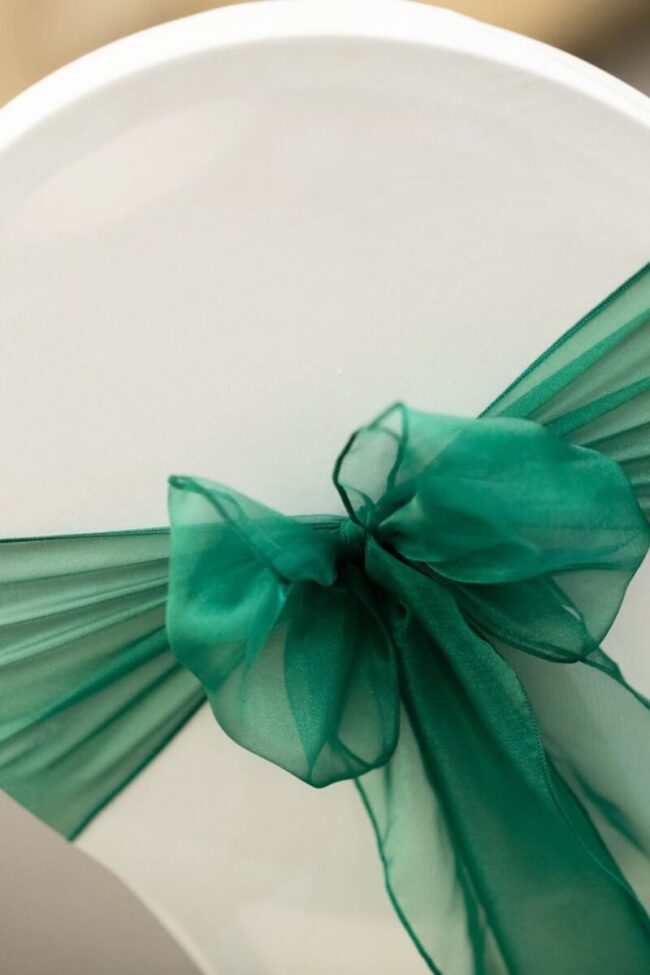 Hunter green sashes tied in a bow on a white chair cover