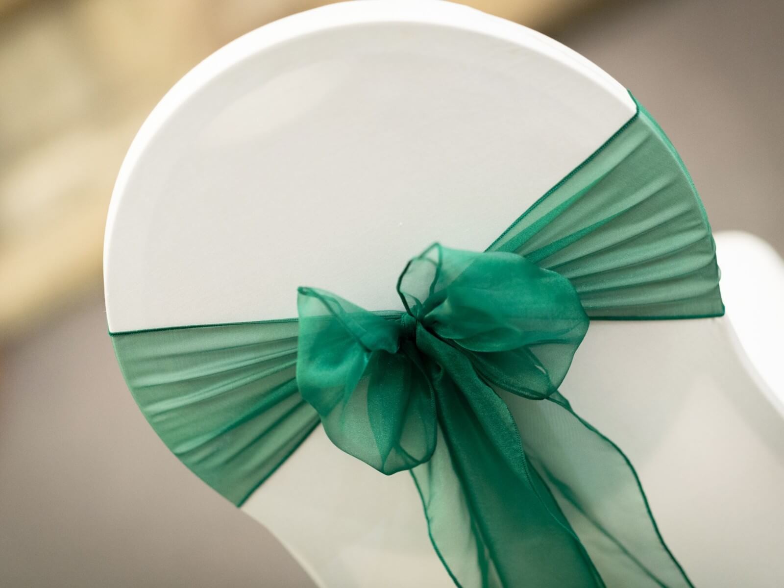 Hunter green sashes tied in a bow on a white chair cover