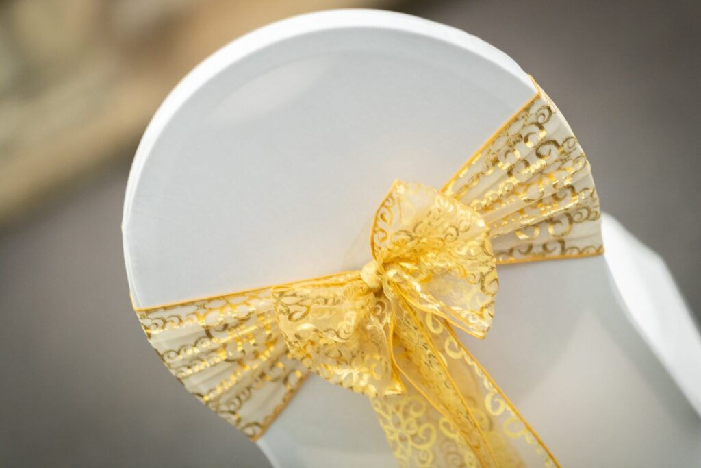 Gold organza sashes tied in a bow on a white chair cover