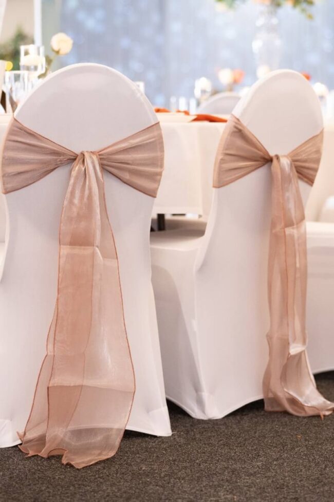 Champagne chair sashes styled across venue chairs