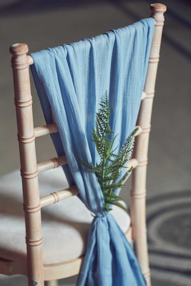 Blue chair drape for hire styled on an open-back chair