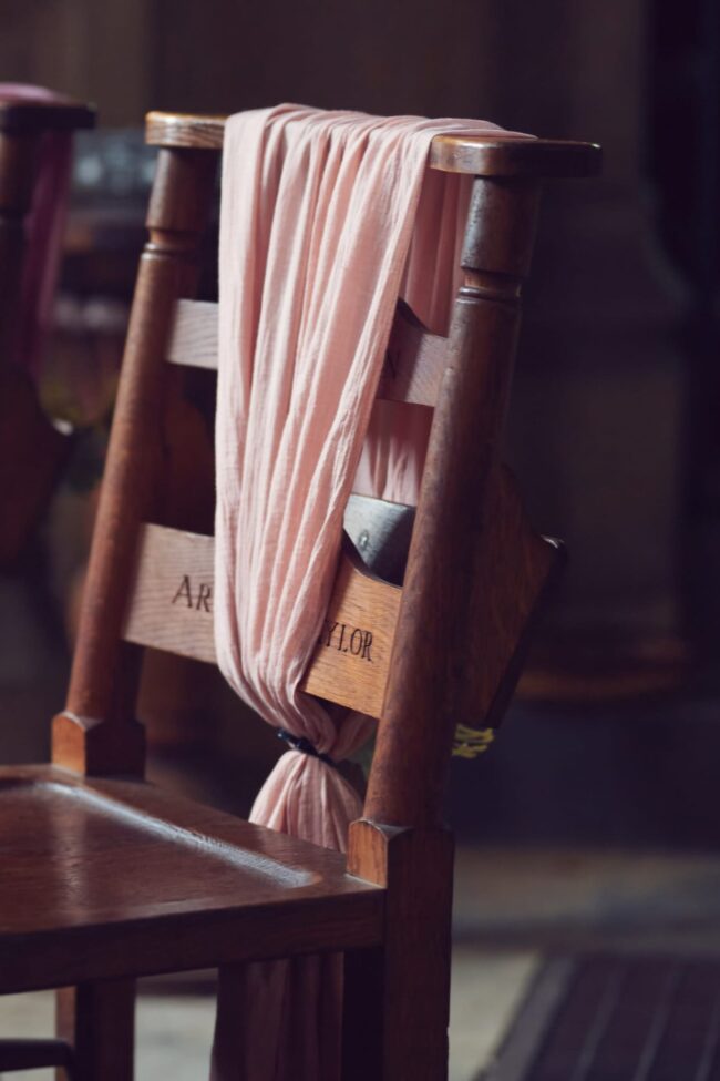 Blush pink cheesecloth chair drape styled over a wooden chair
