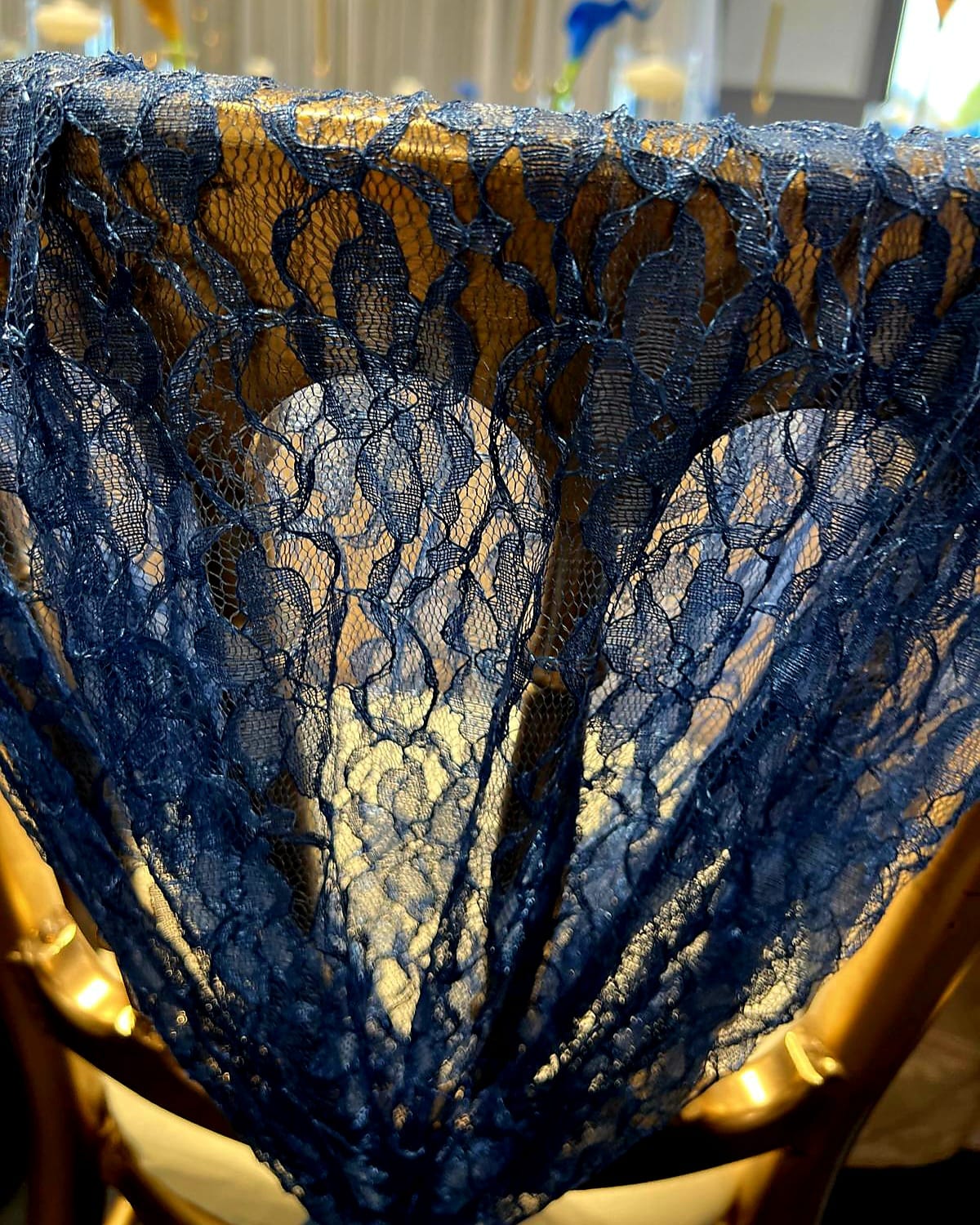 Close-up of navy lace chair drape showing the floral lace texture