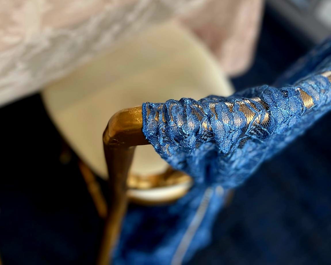 Navy lace chair drape gathered over the top rail of a chair