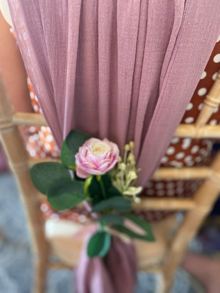 Mauve chair drape for hire styled with a small floral accent