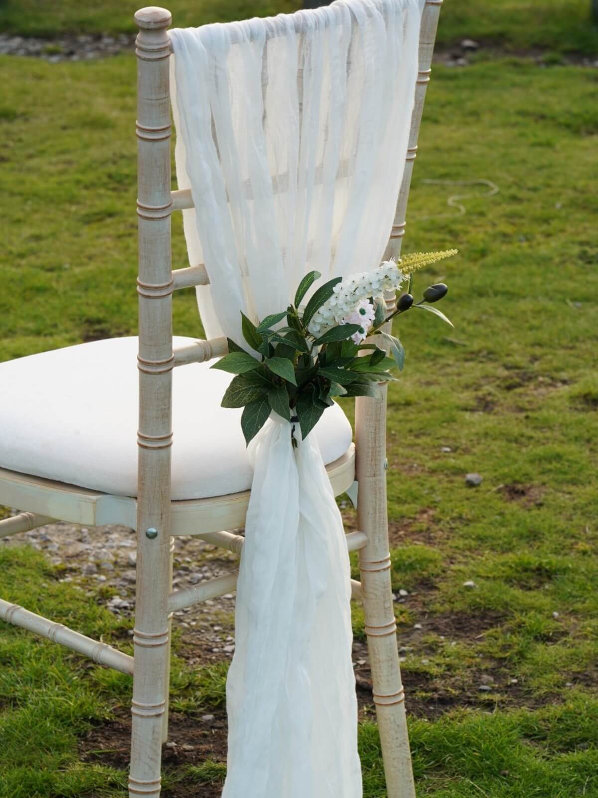 White cheesecloth drape styled on a chiavari chair with greenery detail