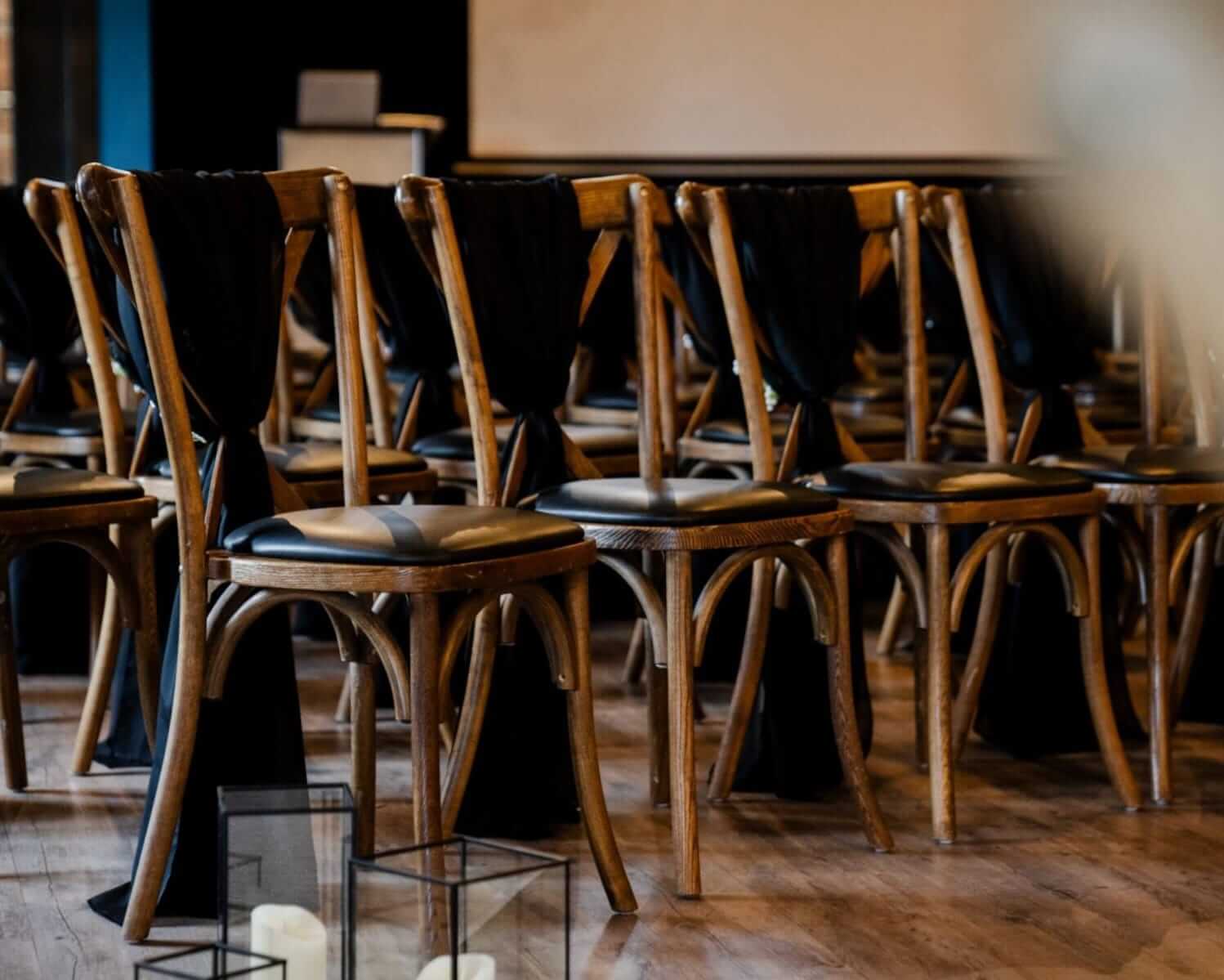 Rows of wooden chairs styled with black chiffon drapes in a ceremony layout