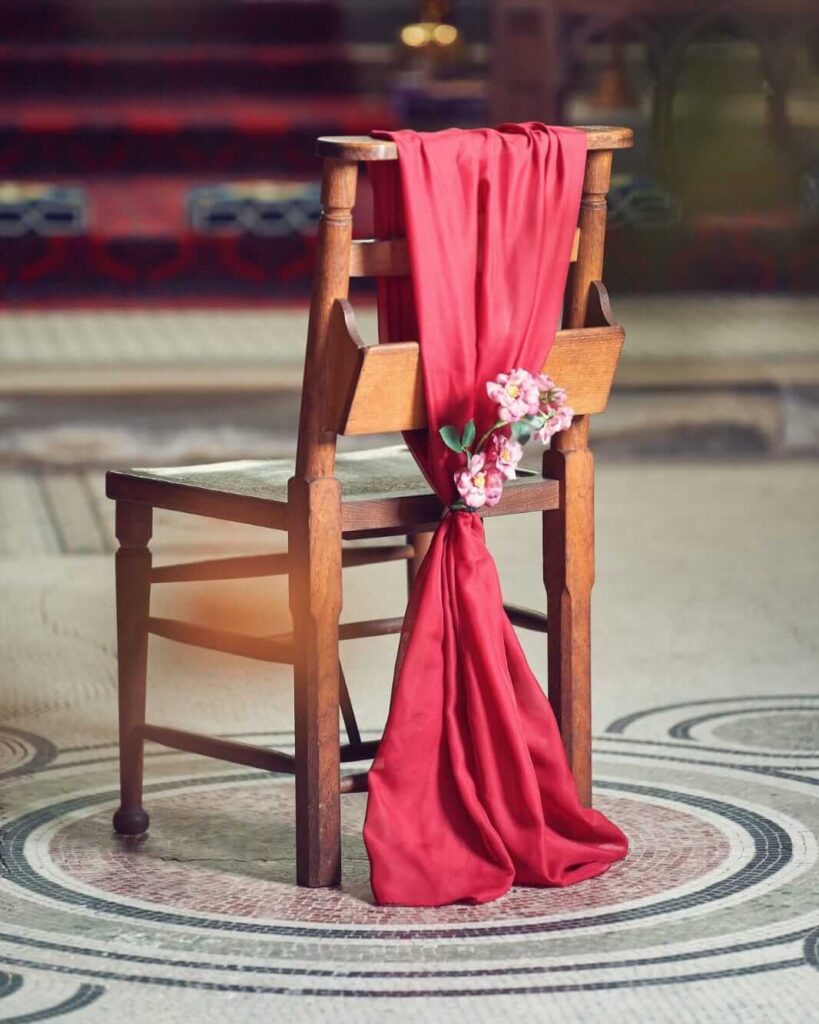 Red chiffon chair drape styled down the back of a wooden chair