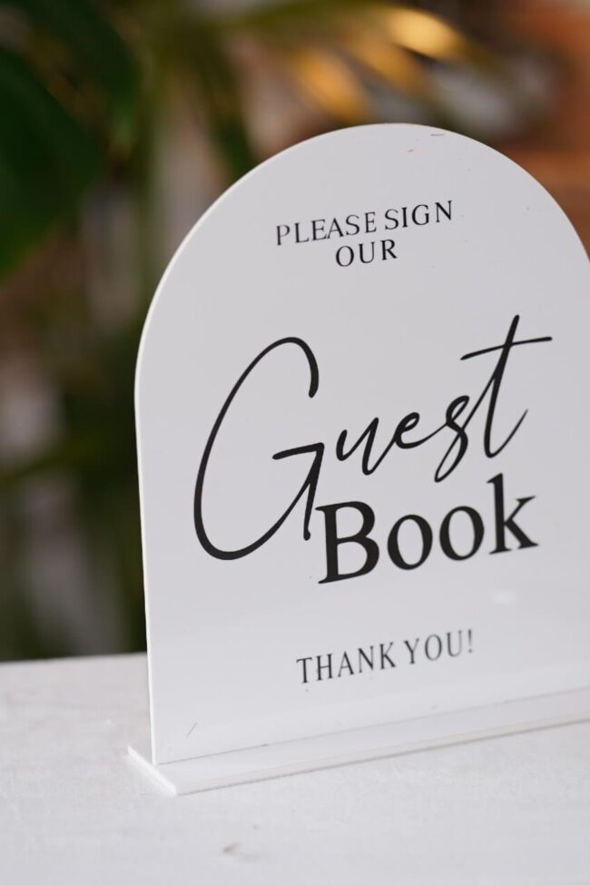 Guest book sign on an acrylic stand for a stationery table