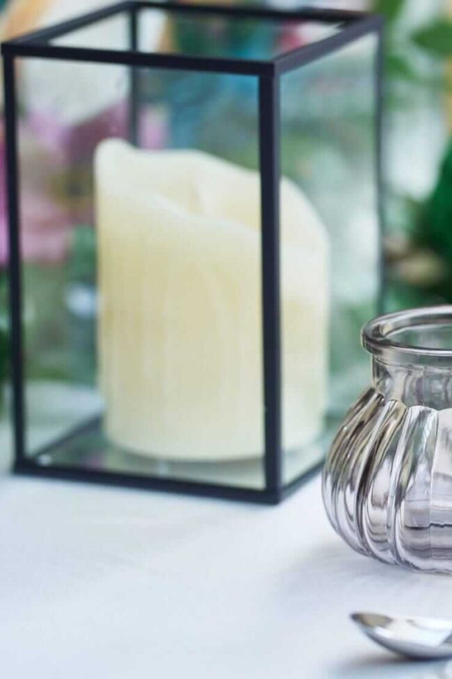 Black hurricane lantern with LED pillar candle inside a glass lantern frame